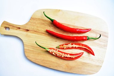 Kırmızı ve yeşil kırmızı kırmızı biber dilimleri / yarısı ahşap kesim tahtasından izole edilmiş beyaz arka plan, deri döşeme, üst manzara, Tayland biberi beyaz masa