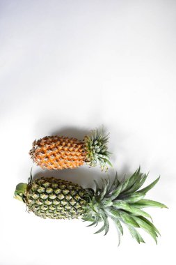 Yeşil ananas ve portakal ananasları, parlak sarı arka planda izole edilmiş taze tropikal meyve arka planında, yaz / bayram, yiyecek ve içecek, sulu, serin, vegan, sağlıklı gıda, fitness