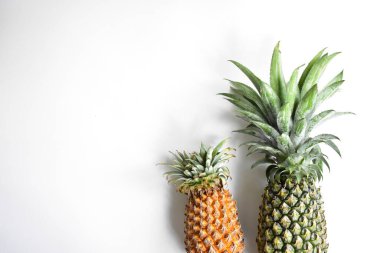 Yeşil ananas ve portakal ananasları, parlak sarı arka planda izole edilmiş taze tropikal meyve arka planında, yaz / bayram, yiyecek ve içecek, sulu, serin, vegan, sağlıklı gıda, fitness