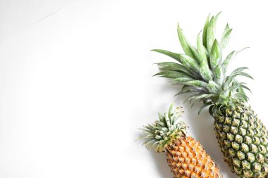 Yeşil ananas ve portakal ananasları, parlak sarı arka planda izole edilmiş taze tropikal meyve arka planında, yaz / bayram, yiyecek ve içecek, sulu, serin, vegan, sağlıklı gıda, fitness