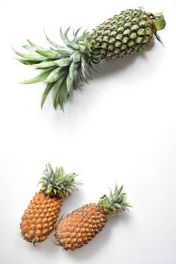 Yeşil ananas ve portakal ananasları, parlak sarı arka planda izole edilmiş taze tropikal meyve arka planında, yaz / bayram, yiyecek ve içecek, sulu, serin, vegan, sağlıklı gıda, fitness