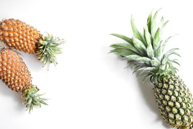 Yeşil ananas ve portakal ananasları, parlak sarı arka planda izole edilmiş taze tropikal meyve arka planında, yaz / bayram, yiyecek ve içecek, sulu, serin, vegan, sağlıklı gıda, fitness