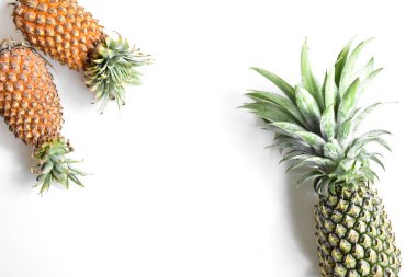 Yeşil ananas ve portakal ananasları, parlak sarı arka planda izole edilmiş taze tropikal meyve arka planında, yaz / bayram, yiyecek ve içecek, sulu, serin, vegan, sağlıklı gıda, fitness