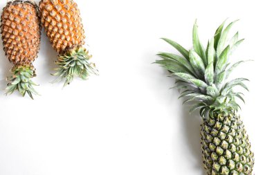 Yeşil ananas ve portakal ananasları, parlak sarı arka planda izole edilmiş taze tropikal meyve arka planında, yaz / bayram, yiyecek ve içecek, sulu, serin, vegan, sağlıklı gıda, fitness