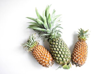 Yeşil ananas ve portakal ananasları, parlak sarı arka planda izole edilmiş taze tropikal meyve arka planında, yaz / bayram, yiyecek ve içecek, sulu, serin, vegan, sağlıklı gıda, fitness