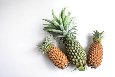 Yeşil ananas ve portakal ananasları, parlak sarı arka planda izole edilmiş taze tropikal meyve arka planında, yaz / bayram, yiyecek ve içecek, sulu, serin, vegan, sağlıklı gıda, fitness