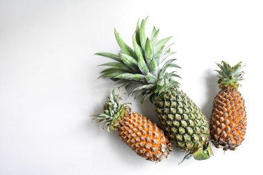 Yeşil ananas ve portakal ananasları, parlak sarı arka planda izole edilmiş taze tropikal meyve arka planında, yaz / bayram, yiyecek ve içecek, sulu, serin, vegan, sağlıklı gıda, fitness