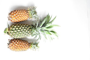 Yeşil ananas ve portakal ananasları, parlak sarı arka planda izole edilmiş taze tropikal meyve arka planında, yaz / bayram, yiyecek ve içecek, sulu, serin, vegan, sağlıklı gıda, fitness