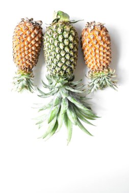 Yeşil ananas ve portakal ananasları, parlak sarı arka planda izole edilmiş taze tropikal meyve arka planında, yaz / bayram, yiyecek ve içecek, sulu, serin, vegan, sağlıklı gıda, fitness