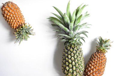 Yeşil ananas ve portakal ananasları, parlak sarı arka planda izole edilmiş taze tropikal meyve arka planında, yaz / bayram, yiyecek ve içecek, sulu, serin, vegan, sağlıklı gıda, fitness