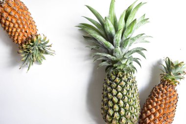 Yeşil ananas ve portakal ananasları, parlak sarı arka planda izole edilmiş taze tropikal meyve arka planında, yaz / bayram, yiyecek ve içecek, sulu, serin, vegan, sağlıklı gıda, fitness