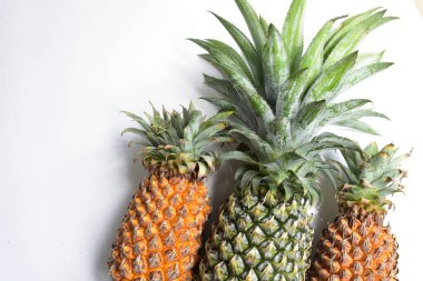 Yeşil ananas ve portakal ananasları, parlak sarı arka planda izole edilmiş taze tropikal meyve arka planında, yaz / bayram, yiyecek ve içecek, sulu, serin, vegan, sağlıklı gıda, fitness