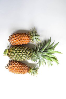 Yeşil ananas ve portakal ananasları, parlak sarı arka planda izole edilmiş taze tropikal meyve arka planında, yaz / bayram, yiyecek ve içecek, sulu, serin, vegan, sağlıklı gıda, fitness