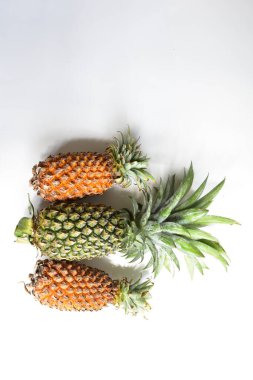Yeşil ananas ve portakal ananasları, parlak sarı arka planda izole edilmiş taze tropikal meyve arka planında, yaz / bayram, yiyecek ve içecek, sulu, serin, vegan, sağlıklı gıda, fitness