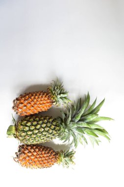Yeşil ananas ve portakal ananasları, parlak sarı arka planda izole edilmiş taze tropikal meyve arka planında, yaz / bayram, yiyecek ve içecek, sulu, serin, vegan, sağlıklı gıda, fitness