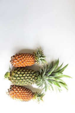 Yeşil ananas ve portakal ananasları, parlak sarı arka planda izole edilmiş taze tropikal meyve arka planında, yaz / bayram, yiyecek ve içecek, sulu, serin, vegan, sağlıklı gıda, fitness