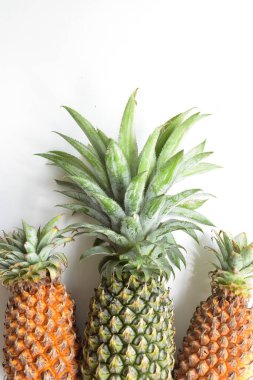 Yeşil ananas ve portakal ananasları, parlak sarı arka planda izole edilmiş taze tropikal meyve arka planında, yaz / bayram, yiyecek ve içecek, sulu, serin, vegan, sağlıklı gıda, fitness