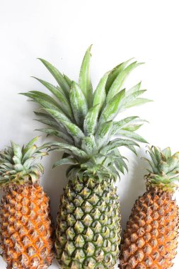 Yeşil ananas ve portakal ananasları, parlak sarı arka planda izole edilmiş taze tropikal meyve arka planında, yaz / bayram, yiyecek ve içecek, sulu, serin, vegan, sağlıklı gıda, fitness