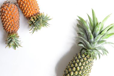 Yeşil ananas ve portakal ananasları, parlak sarı arka planda izole edilmiş taze tropikal meyve arka planında, yaz / bayram, yiyecek ve içecek, sulu, serin, vegan, sağlıklı gıda, fitness