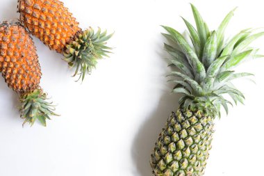 Yeşil ananas ve portakal ananasları, parlak sarı arka planda izole edilmiş taze tropikal meyve arka planında, yaz / bayram, yiyecek ve içecek, sulu, serin, vegan, sağlıklı gıda, fitness