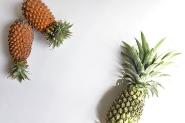 Yeşil ananas ve portakal ananasları, parlak sarı arka planda izole edilmiş taze tropikal meyve arka planında, yaz / bayram, yiyecek ve içecek, sulu, serin, vegan, sağlıklı gıda, fitness