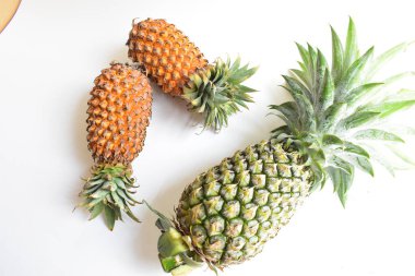 Yeşil ananas ve portakal ananasları, parlak sarı arka planda izole edilmiş taze tropikal meyve arka planında, yaz / bayram, yiyecek ve içecek, sulu, serin, vegan, sağlıklı gıda, fitness