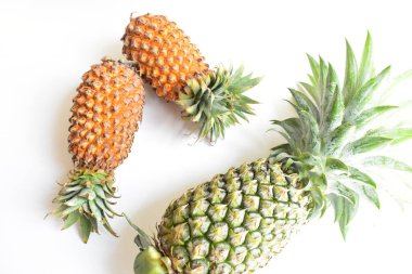 Yeşil ananas ve portakal ananasları, parlak sarı arka planda izole edilmiş taze tropikal meyve arka planında, yaz / bayram, yiyecek ve içecek, sulu, serin, vegan, sağlıklı gıda, fitness