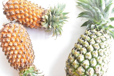 Yeşil ananas ve portakal ananasları, parlak sarı arka planda izole edilmiş taze tropikal meyve arka planında, yaz / bayram, yiyecek ve içecek, sulu, serin, vegan, sağlıklı gıda, fitness