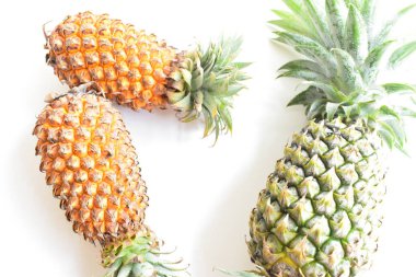 Yeşil ananas ve portakal ananasları, parlak sarı arka planda izole edilmiş taze tropikal meyve arka planında, yaz / bayram, yiyecek ve içecek, sulu, serin, vegan, sağlıklı gıda, fitness