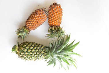 Yeşil ananas ve portakal ananasları, parlak sarı arka planda izole edilmiş taze tropikal meyve arka planında, yaz / bayram, yiyecek ve içecek, sulu, serin, vegan, sağlıklı gıda, fitness