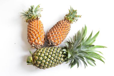 Yeşil ananas ve portakal ananasları, parlak sarı arka planda izole edilmiş taze tropikal meyve arka planında, yaz / bayram, yiyecek ve içecek, sulu, serin, vegan, sağlıklı gıda, fitness