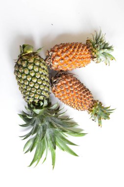 Yeşil ananas ve portakal ananasları, parlak sarı arka planda izole edilmiş taze tropikal meyve arka planında, yaz / bayram, yiyecek ve içecek, sulu, serin, vegan, sağlıklı gıda, fitness