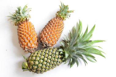 Yeşil ananas ve portakal ananasları, parlak sarı arka planda izole edilmiş taze tropikal meyve arka planında, yaz / bayram, yiyecek ve içecek, sulu, serin, vegan, sağlıklı gıda, fitness