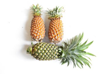 Yeşil ananas ve portakal ananasları, parlak sarı arka planda izole edilmiş taze tropikal meyve arka planında, yaz / bayram, yiyecek ve içecek, sulu, serin, vegan, sağlıklı gıda, fitness
