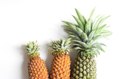 Yeşil ananas ve portakal ananasları, parlak sarı arka planda izole edilmiş taze tropikal meyve arka planında, yaz / bayram, yiyecek ve içecek, sulu, serin, vegan, sağlıklı gıda, fitness