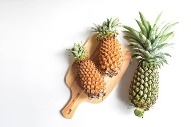 Yeşil ananas ve portakal ananasları, parlak sarı arka planda izole edilmiş taze tropikal meyve arka planında, yaz / bayram, yiyecek ve içecek, sulu, serin, vegan, sağlıklı gıda, fitness