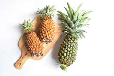 Yeşil ananas ve portakal ananasları, parlak sarı arka planda izole edilmiş taze tropikal meyve arka planında, yaz / bayram, yiyecek ve içecek, sulu, serin, vegan, sağlıklı gıda, fitness