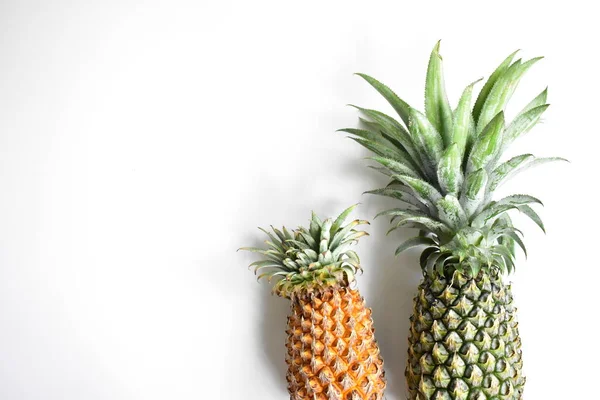 Yeşil ananas ve portakal ananasları, parlak sarı arka planda izole edilmiş taze tropikal meyve arka planında, yaz / bayram, yiyecek ve içecek, sulu, serin, vegan, sağlıklı gıda, fitness