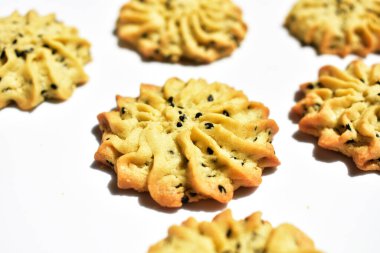 Çiçek biçimli ev yapımı tereyağlı kurabiyeler, güneşli parlak ışık ve beyaz arka planda gölgelerle yakın çekim