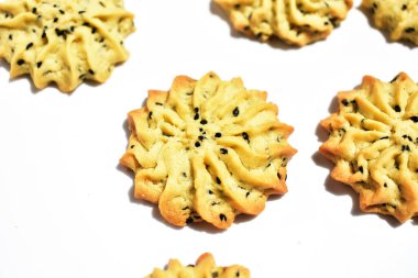 Çiçek biçimli ev yapımı tereyağlı kurabiyeler, güneşli parlak ışık ve beyaz arka planda gölgelerle yakın çekim