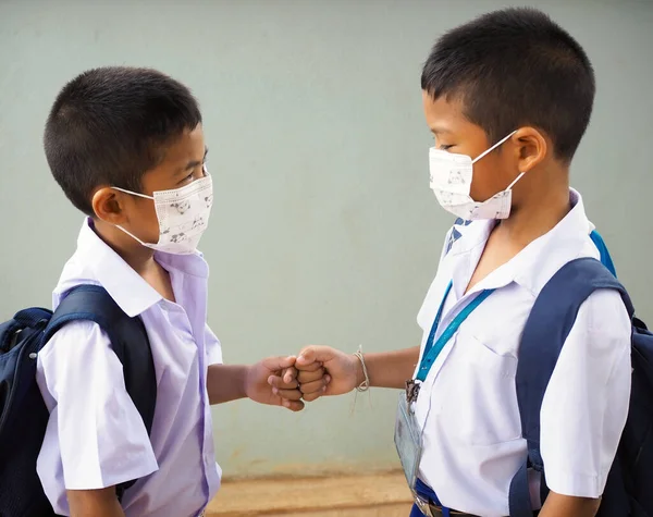 Students wearing masks to protect against viruses and  fist bumping. It\'s a new greeting during the COVID-19 virus outbreak. new normal concept. Corona virus.
