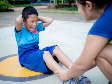 Annesinin desteğiyle egzersiz yapan bir çocuk..