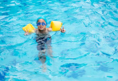 Çocuk havuzda yüzme alıştırması yapıyor.