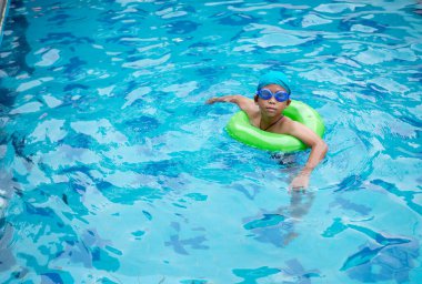 Çocuk havuzda yüzme alıştırması yapıyor.