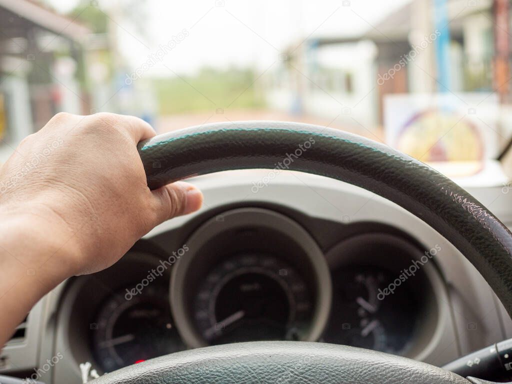 A man's hand holding a car steering wheel To steer the car while driving. Concept of business direction Following the plan.