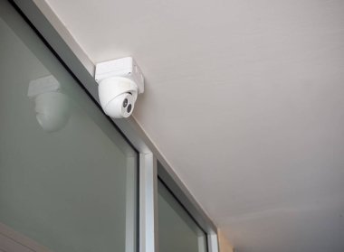 Güvenlik kamerası beyaz tavanın altındaki duvarda..