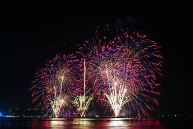 Kutlama gecesinde inanılmaz güzel renkli havai fişek gösterisi, deniz sahilinde su üzerinde çok renkli yansımalarla gösteriliyor. 