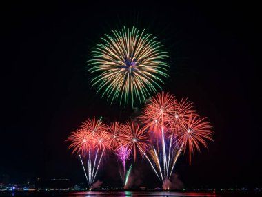 Kutlama gecesinde inanılmaz güzel renkli havai fişek gösterisi, deniz sahilinde su üzerinde çok renkli yansımalarla gösteriliyor. 