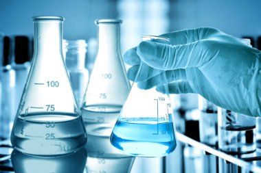 Laboratuvar geçmişi, bilim laboratuarı araştırma ve geliştirme konsepti ve laboratuvar malzemeleriyle dolu bir matarayı tutan bilim adamının eli. 