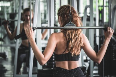 Genç ve çekici kadın spor salonundaki makineyle egzersiz yapıyor..   